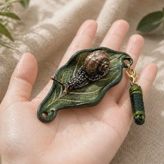 Dije artesanal de hoja de cuero y caracol de bronce para bolso: colgante único inspirado en la naturaleza | Accesorio artístico hecho a mano para bolsos, llaves y regalos