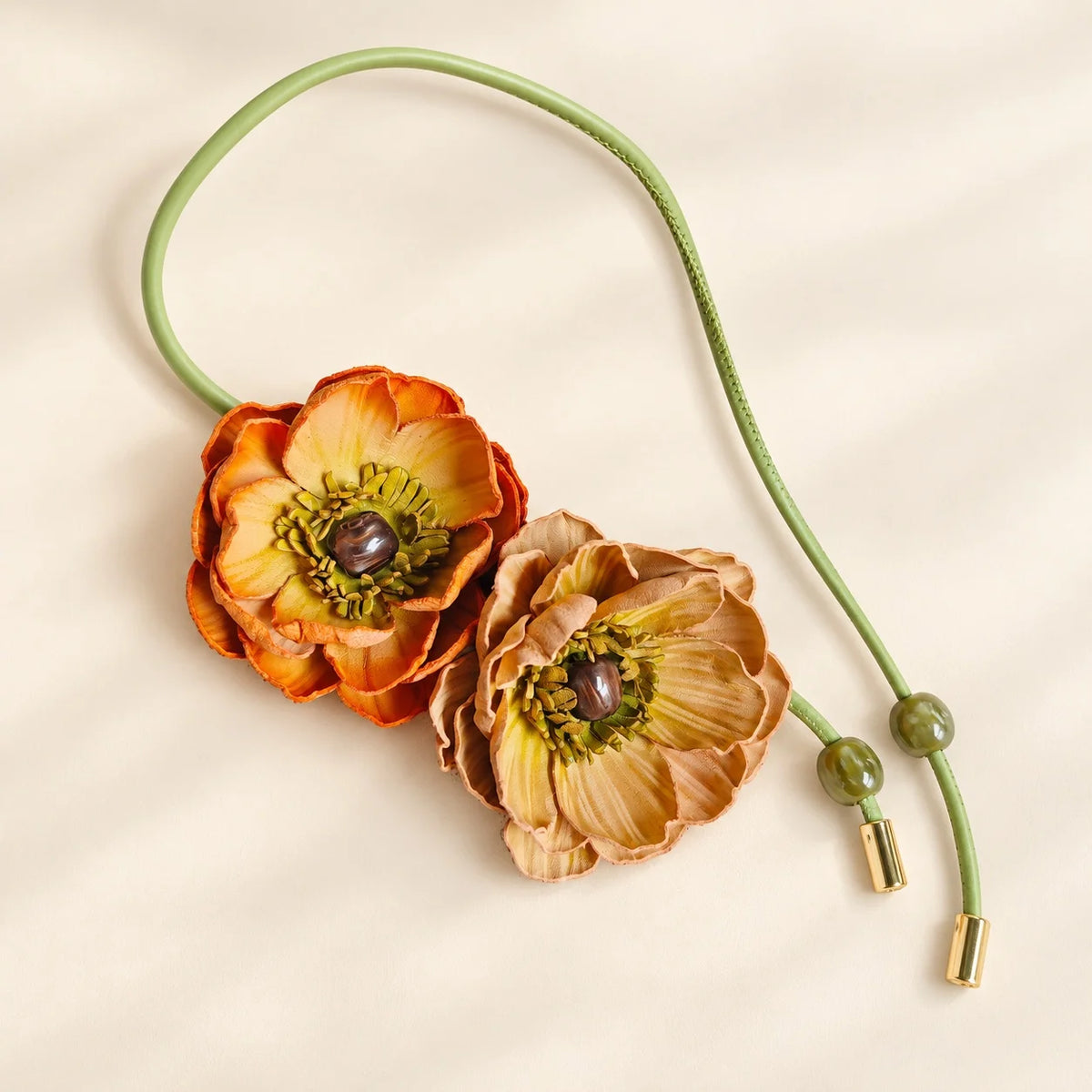 Rose and blush leather double flower bag charm with coral-pink layered petals, green floral centers and dark green cord.