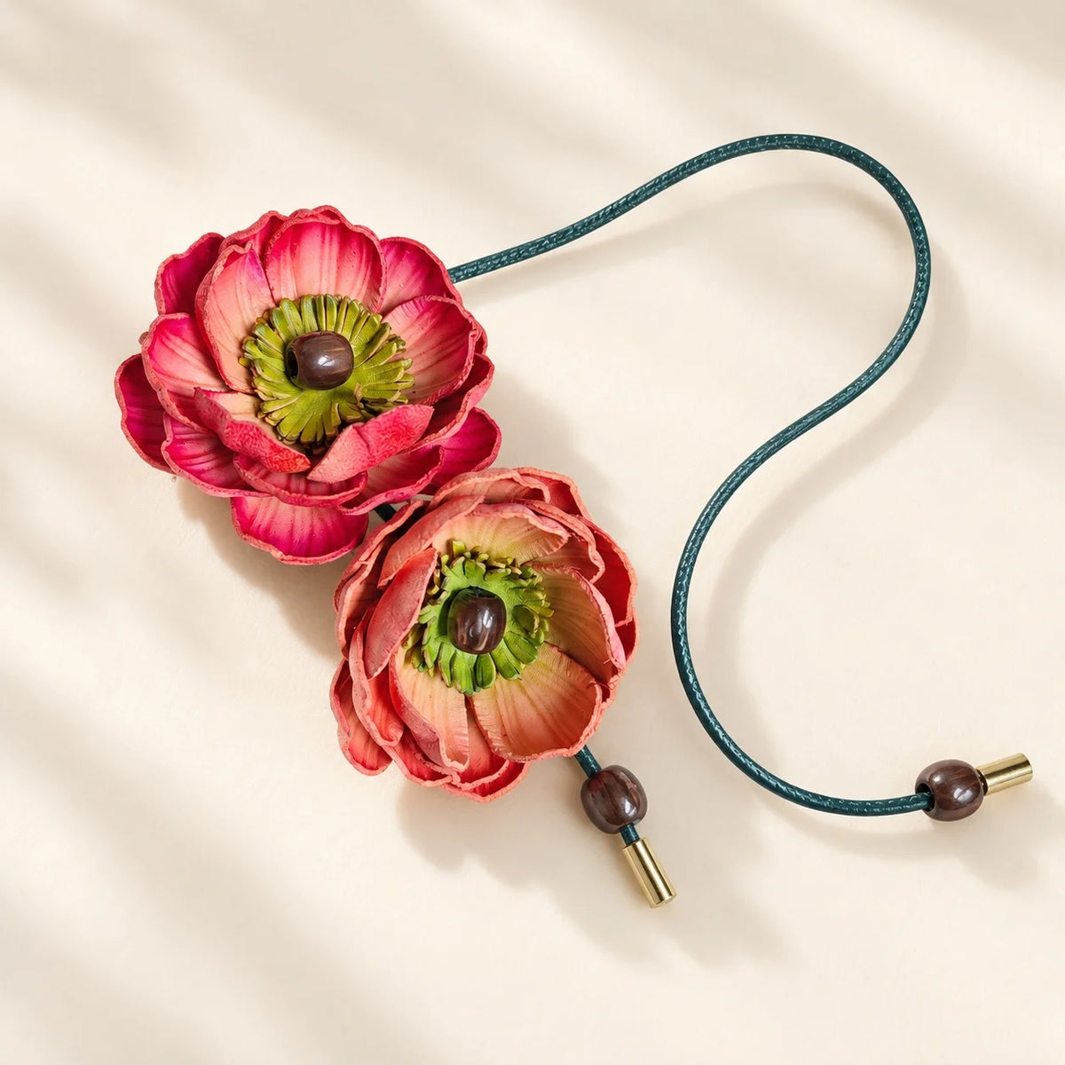 Orange and warm sand sculpted leather double flower bag charm with olive-green cord, round beads and gold-tone tips.