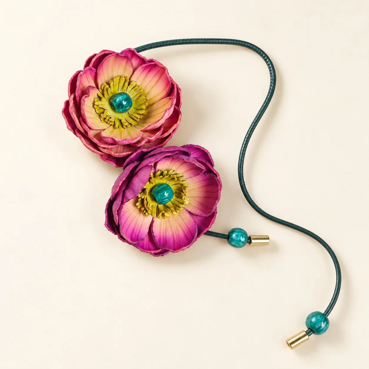 Purple and pink double bloom leather bag charm featuring fuchsia petals, yellow-green floral centers and turquoise decorative beads.