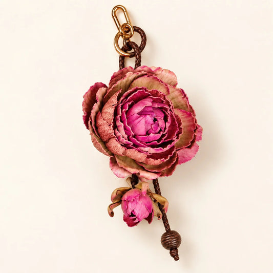 Large pink sculpted cowhide leather rose bag charm with layered petals, hanging flower bud, dark brown braided cord and gold-tone hardware