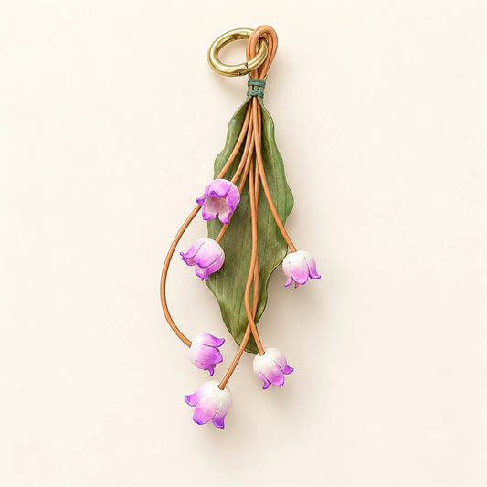 Lavender Valley Bells sculpted cowhide leather bag charm with six purple and ivory flowers, olive-green leaf, and gold-tone ring
