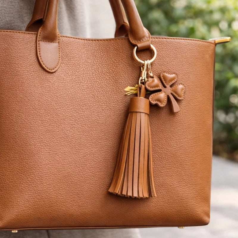 Amuleto de bolsa con borla de cuero Trébol de la suerte – Llavero de cuero plena flor hecho a mano | Elegante colgante de bolso marrón | Regalo simbólico para ella