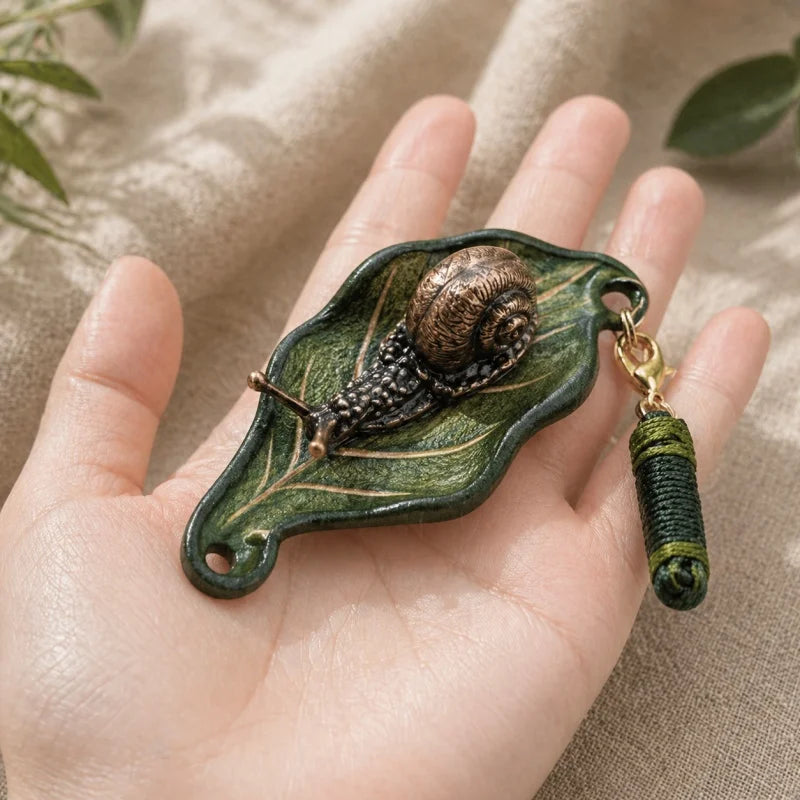 Dije artesanal de hoja de cuero y caracol de bronce para bolso: colgante único inspirado en la naturaleza | Accesorio artístico hecho a mano para bolsos, llaves y regalos