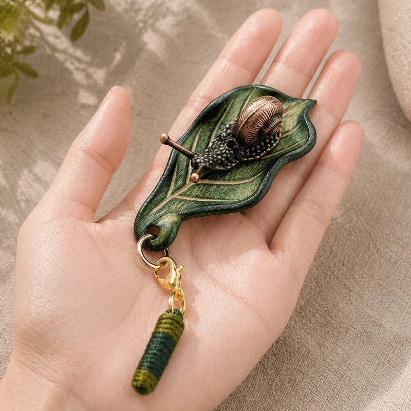 Dije artesanal de hoja de cuero y caracol de bronce para bolso: colgante único inspirado en la naturaleza | Accesorio artístico hecho a mano para bolsos, llaves y regalos